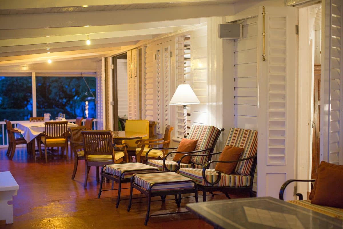 The veranda lounge with striped sofas, lamps glowing at dusk