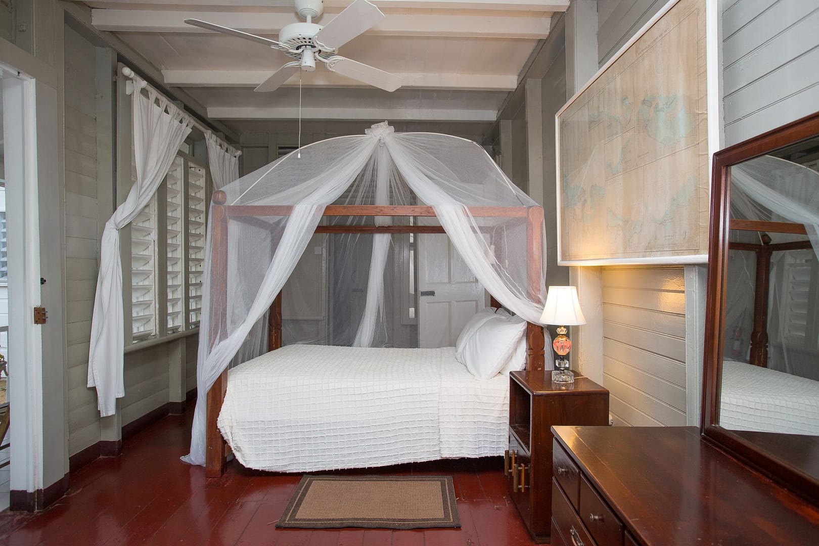 The Garden Master Suite: a four-poster bed draped in white netting beside an old framed map