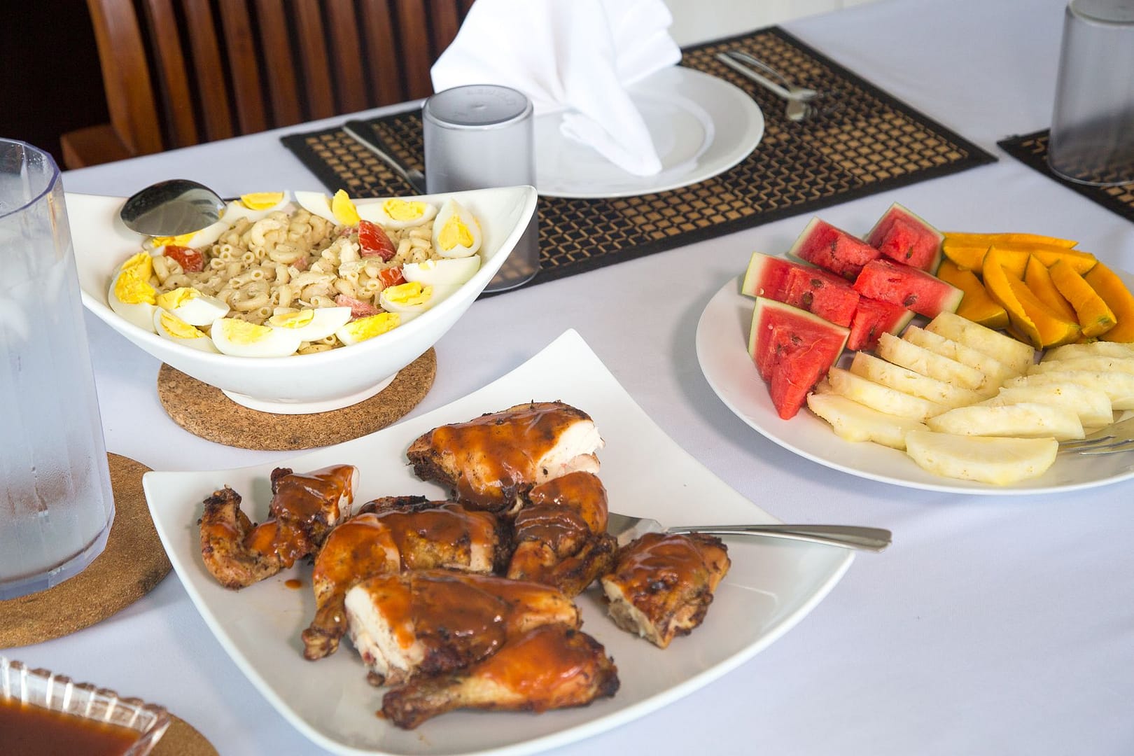 Jerk chicken with rice salad and a plate of watermelon, mango and banana