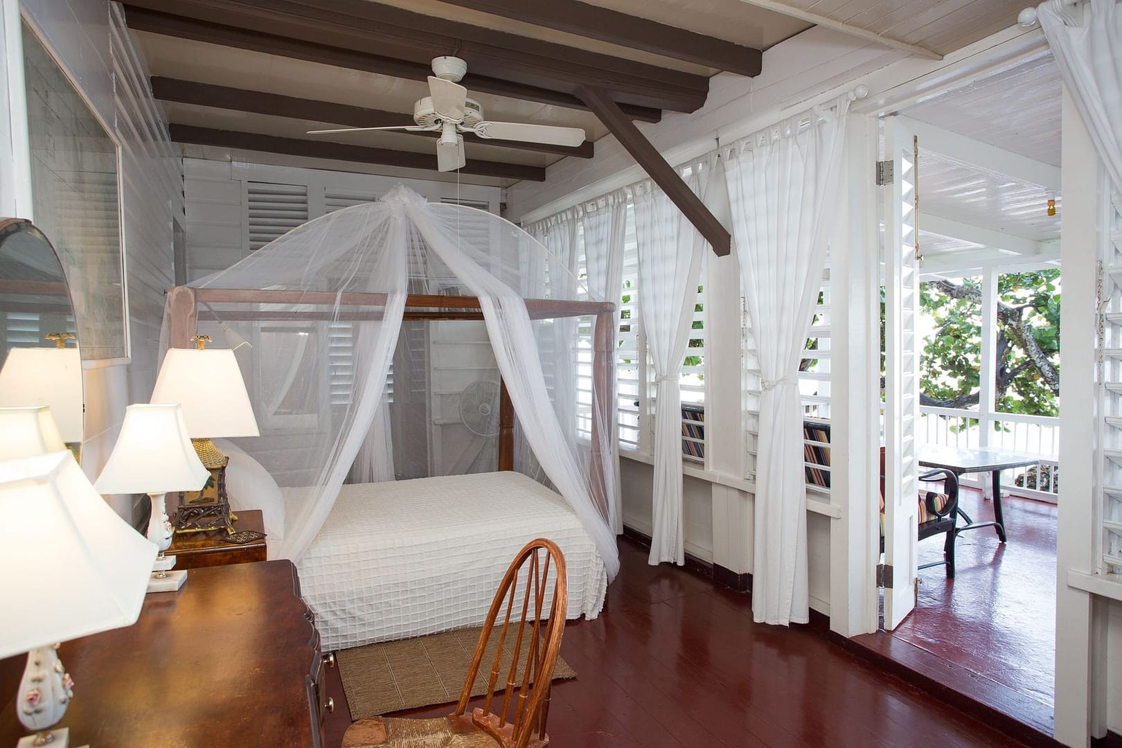The master suite: a netted four-poster bed, with louvred doors open to the veranda and the sea light beyond