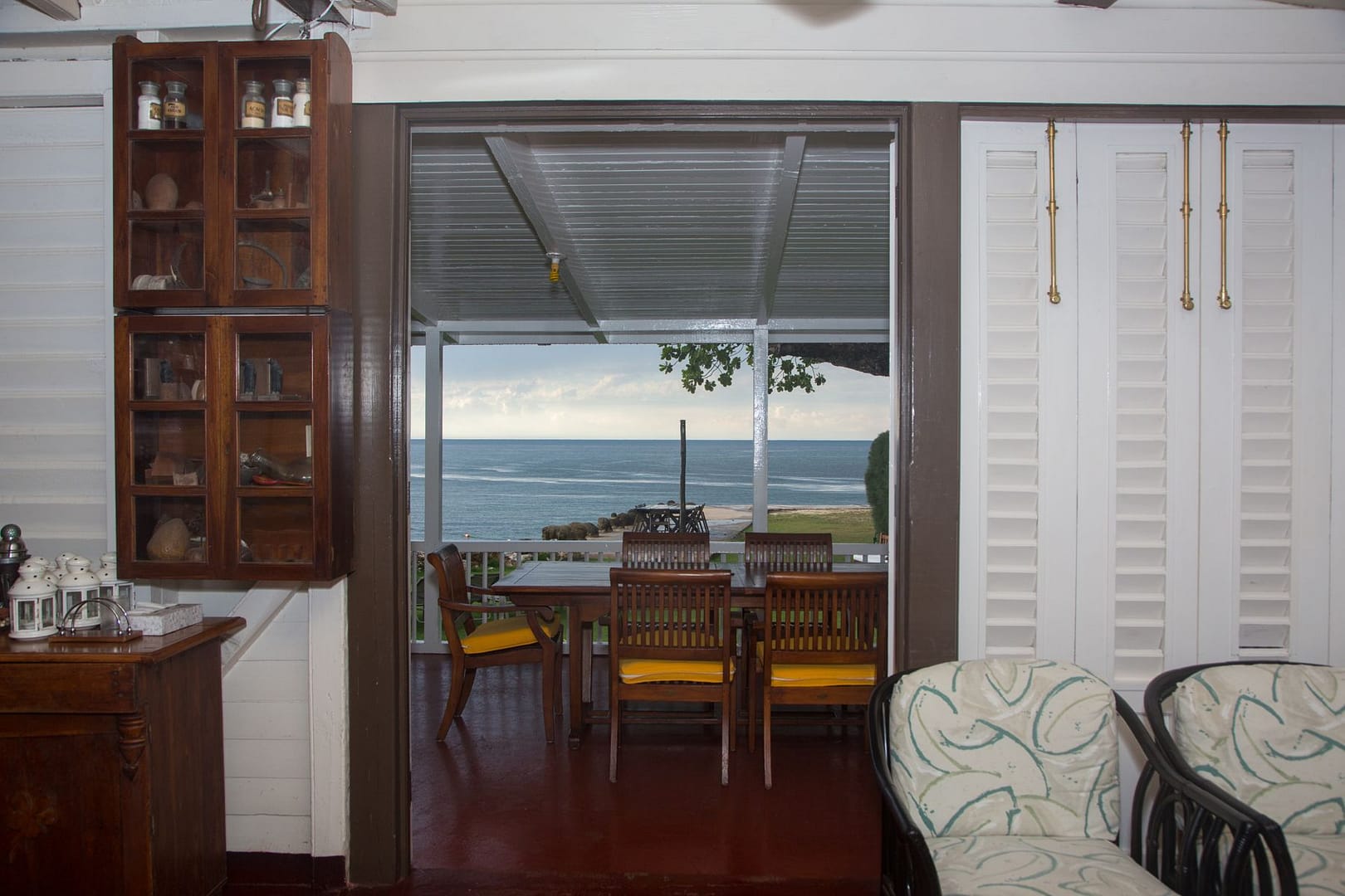 Looking out through open doors to the dining table on the veranda, with the sea beyond