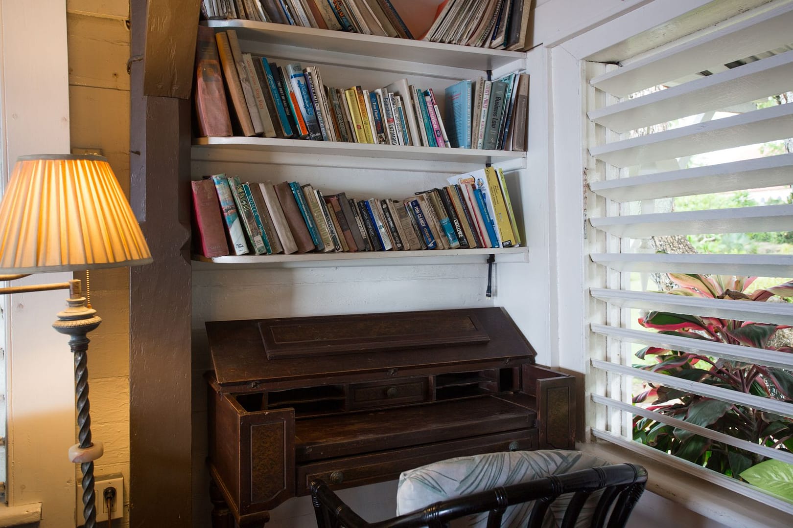 A writing nook with a desk, a lamp and shelves of books
