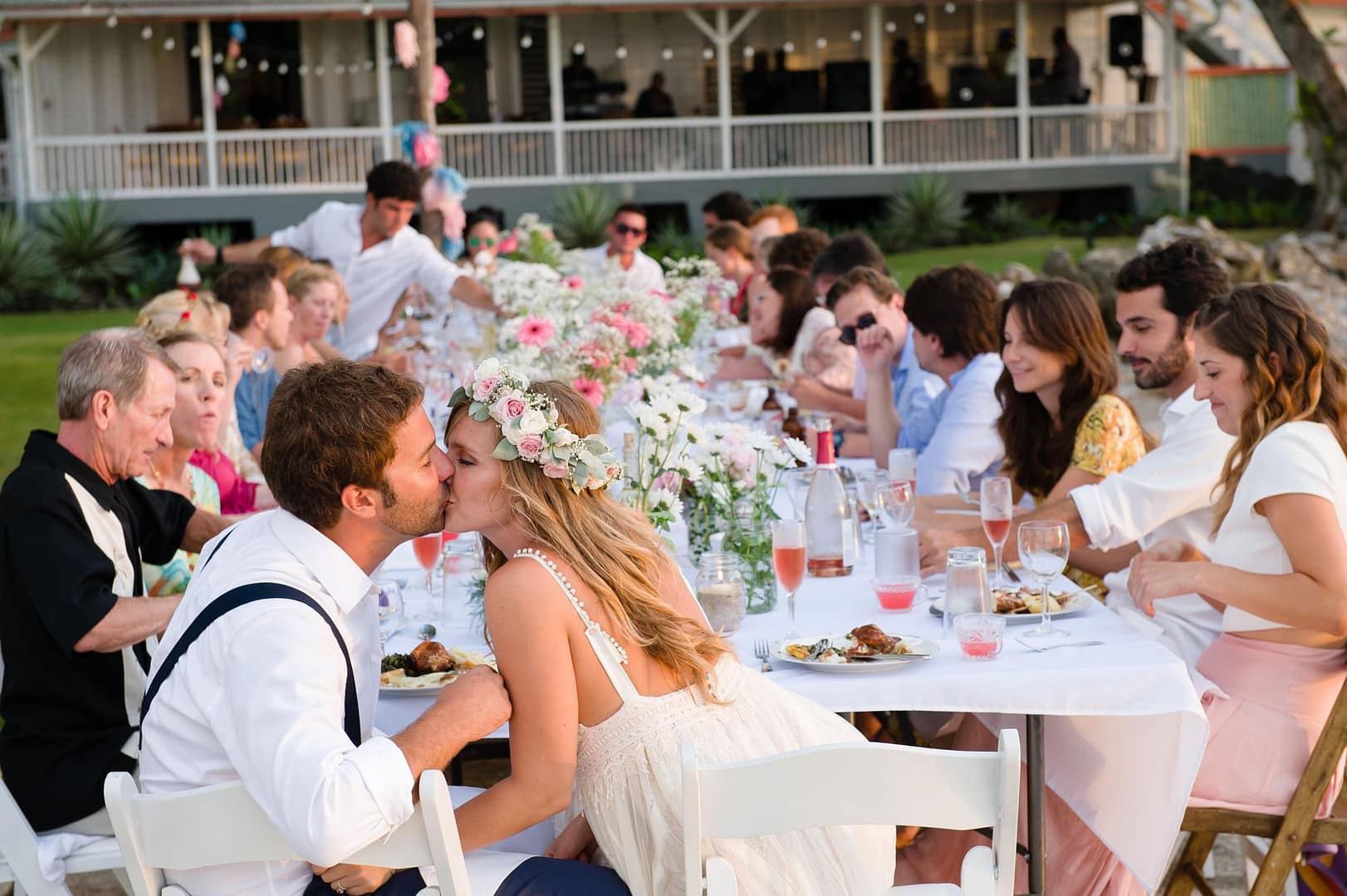 The newlyweds sharing a kiss at a long table full of guests